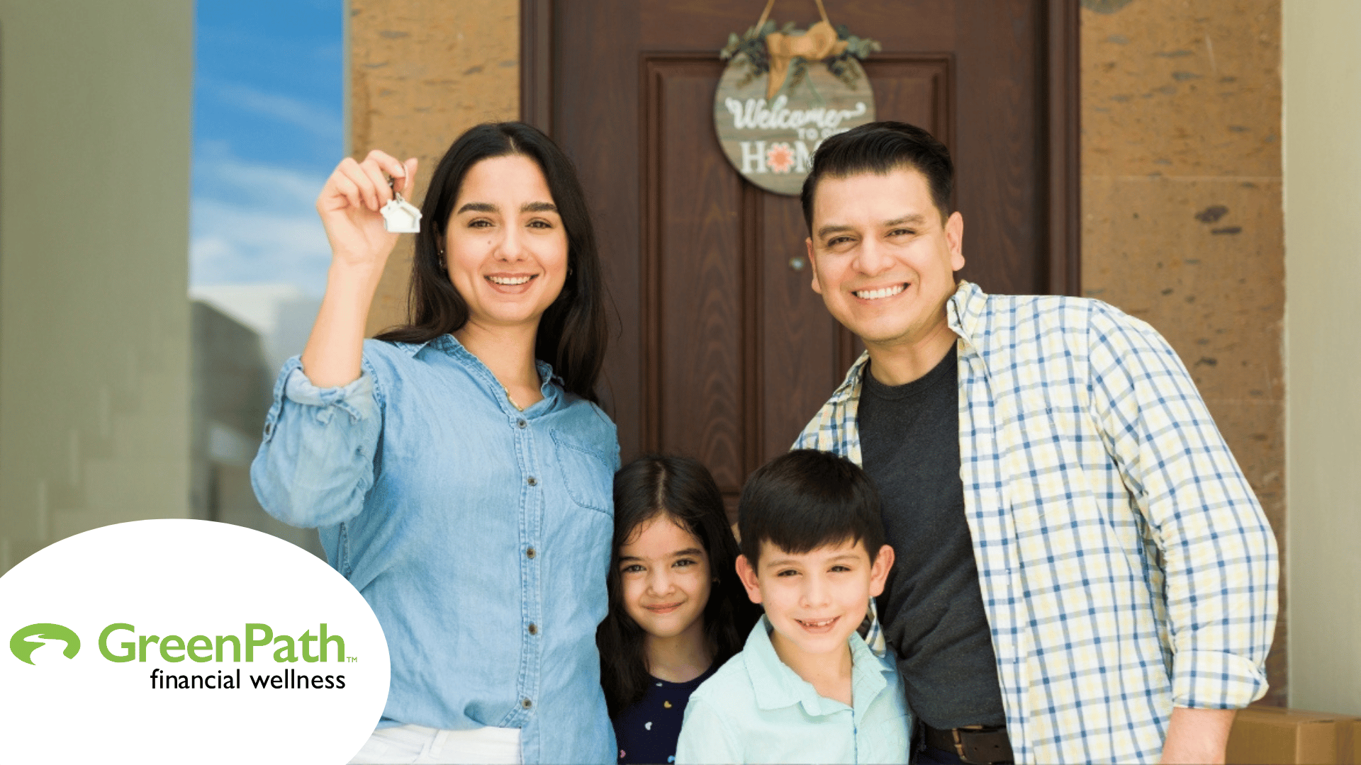 Green Path Financial Wellness Family consisting of dad, mom, and two children standing in front of their new home. Mom is holding up a key. In the bottom left corner, the logo for GreenPath Financial Wellness appears.