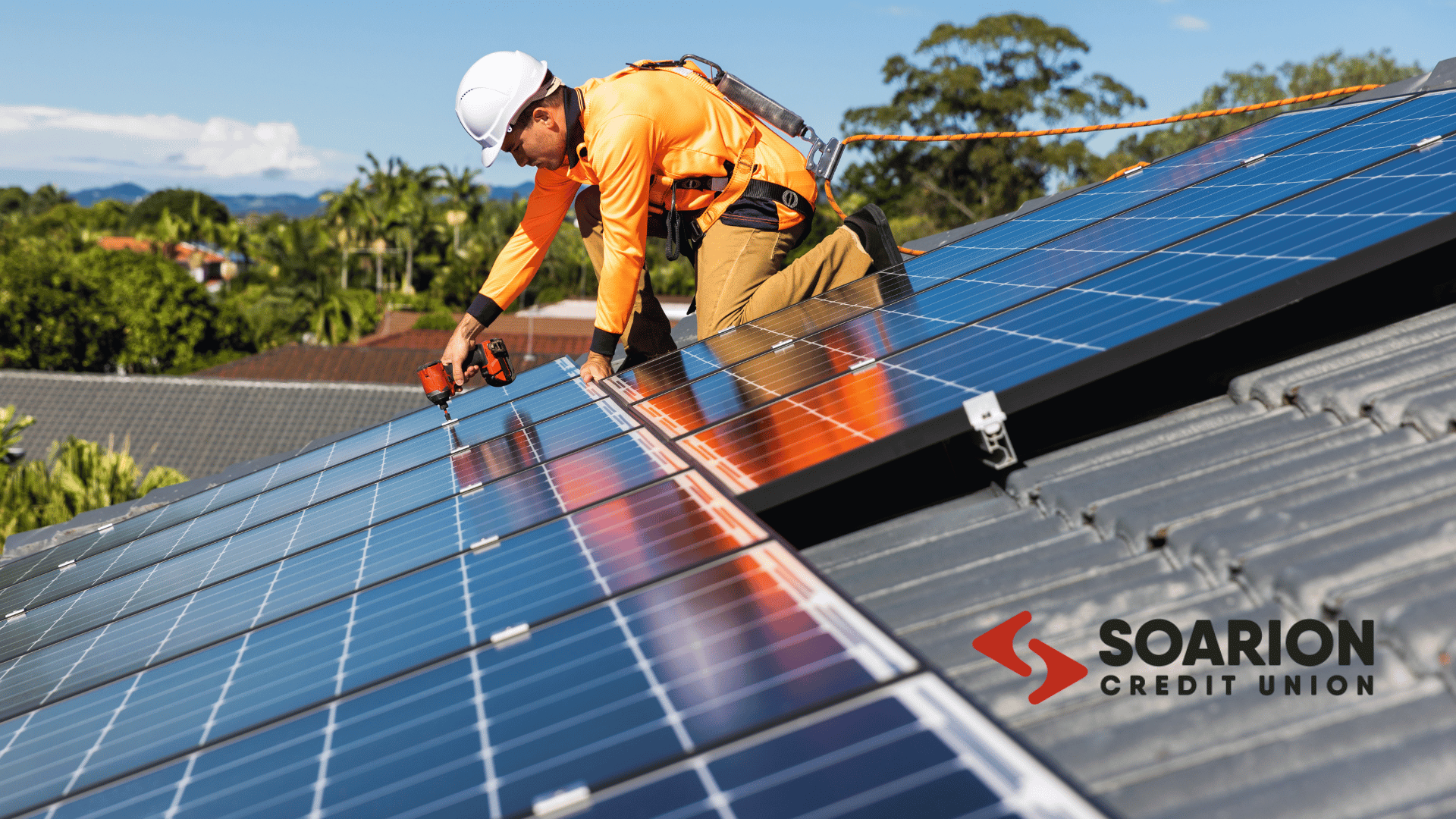 a man affixes solar panels to the roof of a residential building