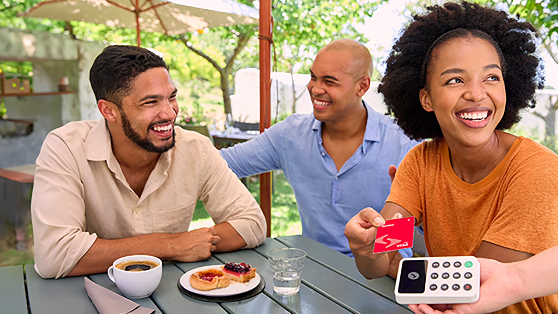 Friends enjoying coffee and pastries on a restaurant patio while using tap to pay card